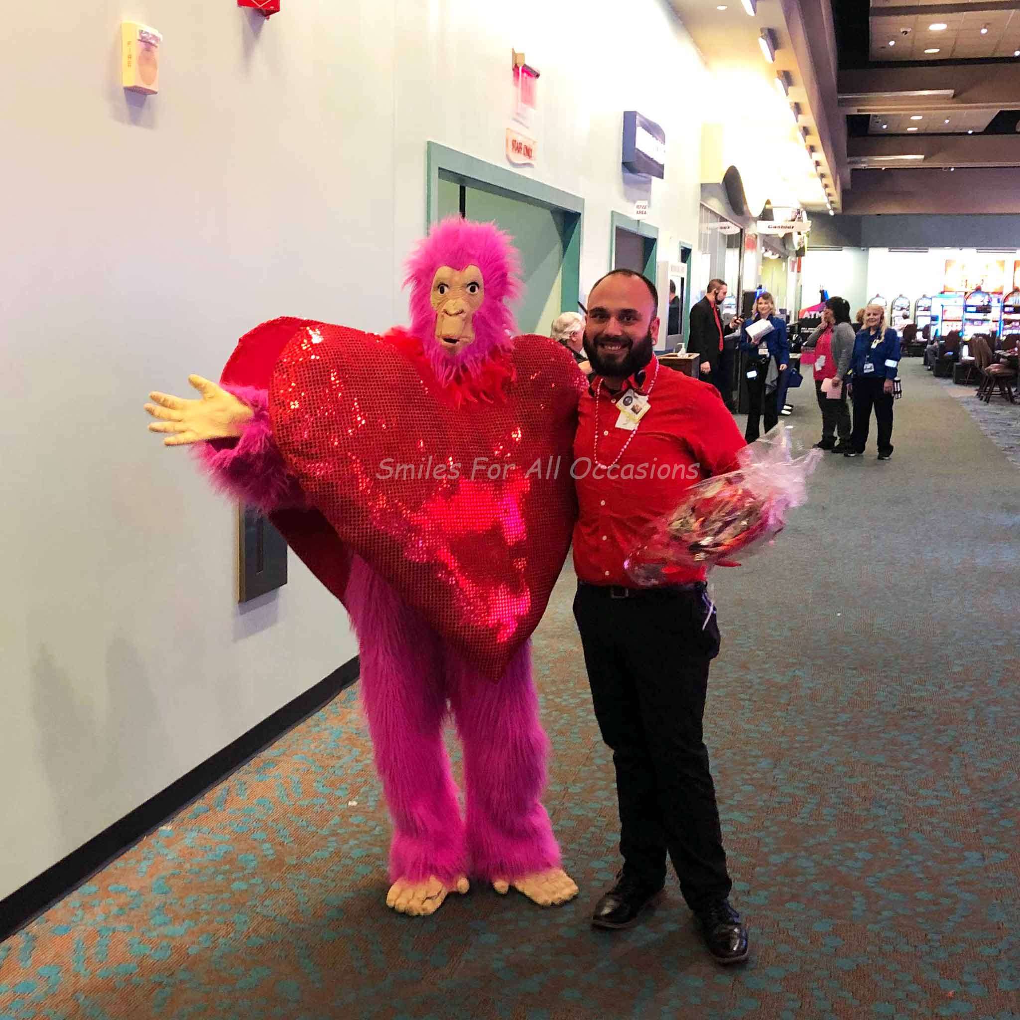 Pink Gorilla with Large Red Heart on Chest Standing with a Man at Casino