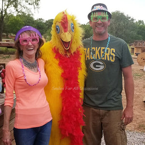 Man and Woman with Birthday Hat and Glasses Next to Chicken Costume